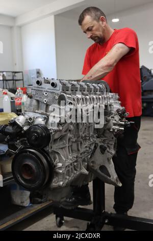 Mechaniker, der am Dieselmotor in der Motorreparatur-Werkstatt arbeitet Stockfoto