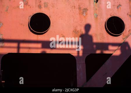 Verschwommener Schatten einer Frau auf der Oberfläche einer großen Metallkonstruktion. Stockfoto