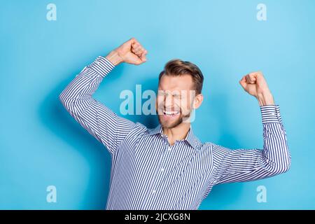 Portrait von erfreut zufrieden Mann geschlossenen Augen heben Fäuste Erreichung isoliert auf blauem Hintergrund Stockfoto