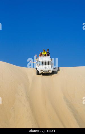 Brasilien, Jericoacoara Touristen genießen eine Fahrt auf einer riesigen Sanddüne, die auf der Rückseite eines Buggys sitzt Stockfoto