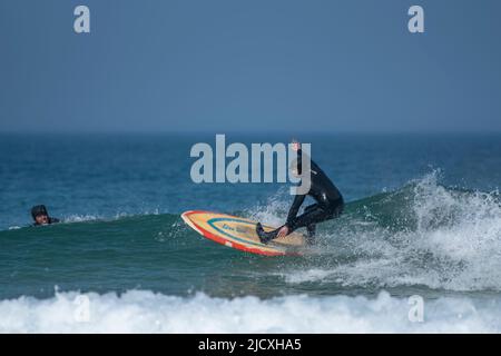 Spektakuläre Surfaktionen, während ein Surfer eine Welle im Fistral in Newquay in Cornwall im Vereinigten Königreich reitet. Stockfoto