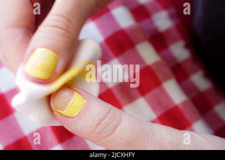 Frau Entfernen Nagellack auf roten Tischtuch Hintergrund Nahaufnahme Stockfoto