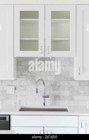 Ein Küchenwaschbecken Detail mit weißen Schränken und einer marmornen U-Bahn-Fliese backsplash aufgenommen. Stockfoto