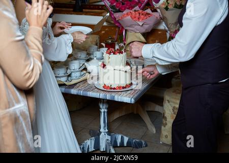 Braut und Bräutigam schneiden den Kuchen Stockfoto