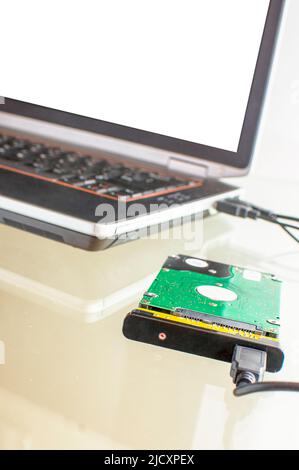 Festplatte, die über USB mit einem isolierten Bildschirm an einen Laptop angeschlossen ist. Festplattendatenrettung. Daten werden gespeichert. Notfall bei Festplattenausfall Stockfoto