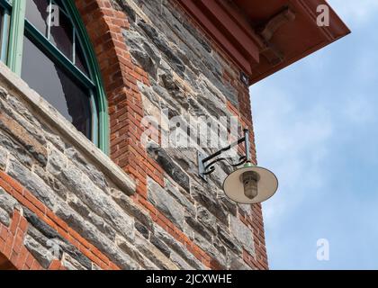 Eine alte Straßenlampe, an der Ecke der Fassade eines Hauses, auf einer Straße Stockfoto