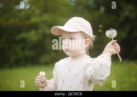 Schönes Kind mit den Blumen des Dandelions im Sommer im Park. Glückliches Kind, das Spaß im Freien hat. Stockfoto