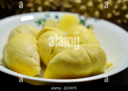 Frischer Durian in der Verpackung auf weißer Schale mit Durian-Schale auf schwarzem Hintergrund des Banners. Durian König der Frucht. Tropische Früchte. Topview von reifen Durian, wo Stockfoto