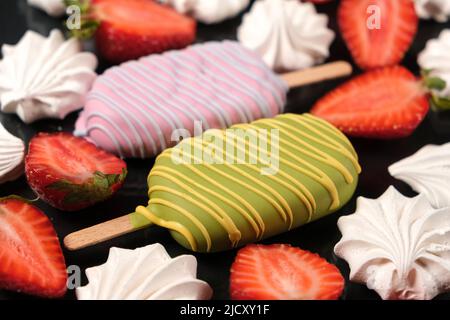 Zwei Eiscremes mit Baiser und Erdbeeren auf schwarzem Hintergrund, Draufsicht. Helle Sommerkarte mit köstlichem Essen und Beeren. Stockfoto
