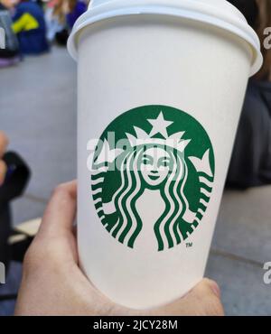 Starbucks Logo auf der Kaffeetasse, die während der Kaffeepause in der Hand gehalten wird. Stockfoto