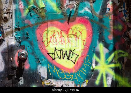 Straßenkunst. Graffiti mit gelbem Herz an der Außentür der Lower East Side von New York City, Vereinigte Staaten von Amerika. Stockfoto