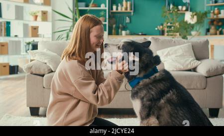 Happy Red haired Teenage Girl Hugs, streichelt ihren Hund, spielt, schaut auf das Tier Stockfoto