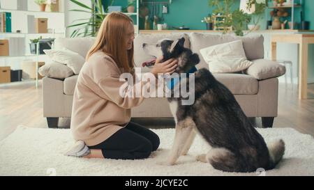 Happy Red haired Teenage Girl Hugs, streichelt ihren Hund, spielt, schaut auf das Tier Stockfoto