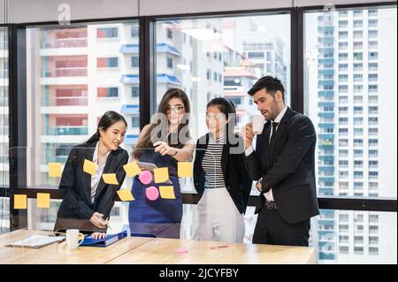 Multiethnische kreative Gruppe von Geschäftsleuten, die in einem modernen Büro im Geschäftsviertel Brainstorming und Haftnotizen auf einem Trenntisch durchführen Stockfoto