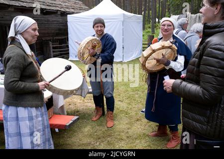 Menschen in traditionellen lettischen Kostümen spielen Tierhauttrommeln im Ethnographischen Freilichtmuseum von Lettland, Riga, Lettland Stockfoto