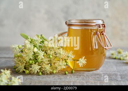 Frische Lindenblüten mit einem Glas Honig auf einem Tisch Stockfoto