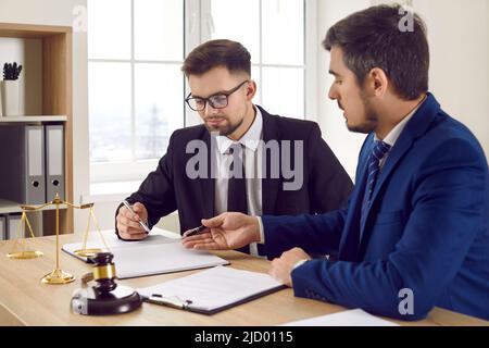 Zwei professionelle männliche Anwälte lesen zusammen juristische Dokumente und studieren Informationen über den Gerichtsfall. Stockfoto