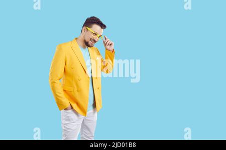 Porträt von fröhlich cool und stilvoll Millennial Mann in buntem Outfit auf hellblauem Hintergrund. Stockfoto
