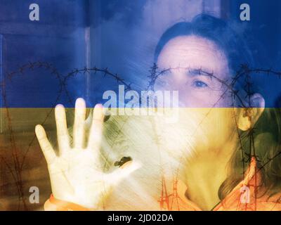 Frau, die aus dem Fenster blickt, mit der Flagge der Ukraine und Stacheldraht überdeckt. Ukraine, Flüchtlinge, Flüchtlinge, Häuser für die Ukraine, psychische Gesundheit, Krieg, Russland Stockfoto