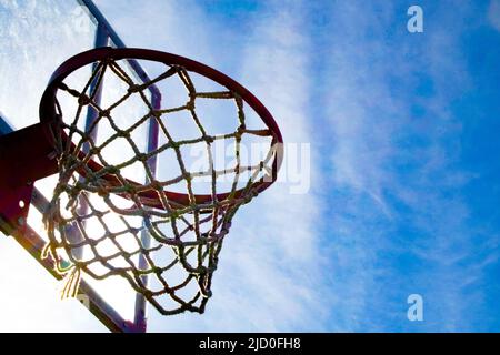 Ein rostiger alter Basketballkorb am Abend gegen einen blauen Himmel. Stockfoto