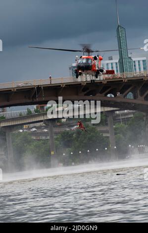 Ein Survival-Techniker der Küstenwache wird von einer Küstenwache-Luftstation Astoria MH-60 Jayhawk-Besatzung in Portland, Oregon, gehisst, 11. Juni 2022. Die Luftbesatzung hatte während des Portland Rose Festivals eine Such- und Rettungsdemonstration durchgeführt. (USA Foto der Küstenwache von Petty Officer, Klasse 3., Diolanda Caballero) Stockfoto