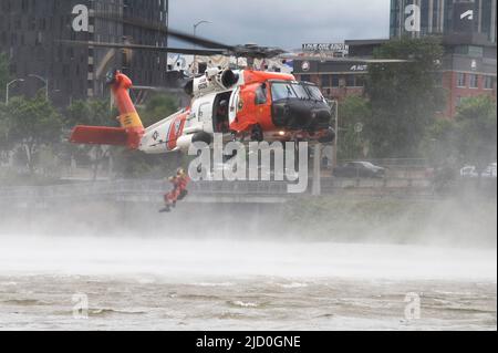 Ein Survival-Techniker der Küstenwache springt von einem Hubschrauber der Air Station Astoria MH-60 Jayhawk in Portland, Oregon, in den Willamette River, 11. Juni 2022. Die Luftbesatzung hatte während des Portland Rose Festivals eine Such- und Rettungsdemonstration durchgeführt. (USA Foto der Küstenwache von Petty Officer, Klasse 3., Diolanda Caballero) Stockfoto