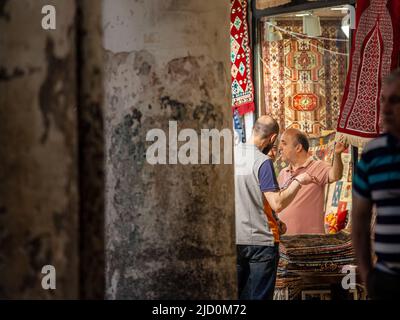 Bild eines Mannes in Kapalicarsi, dem großen Basar von istanbul, türkei, der mit dem Kunden über den Verkauf und Kauf von Teppichen verhandelt. Stockfoto