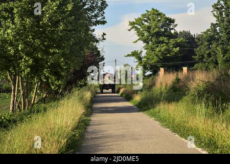 Traktor auf einer kleinen Landstraße bei Sonnenuntergang Stockfoto