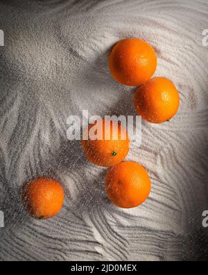 Fünf Mandarinen liegen auf dem Grieß. Hohe Qualität Stockfoto