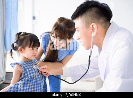 Männlich Kinderarzt halten Stethoskop Prüfung Kind Mädchen Patient Arzt mit Mutter besuchen Stockfoto