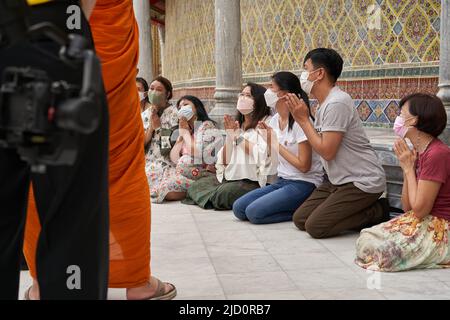 Bangkok, Thailand, 16. februar 2022: Menschen auf den Knien beten während einer buddhistischen Feier Stockfoto