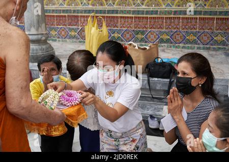 Bangkok, Thailand, 16. februar 2022: Frauen beten und opfern einem Mönch in einem Tempel Stockfoto