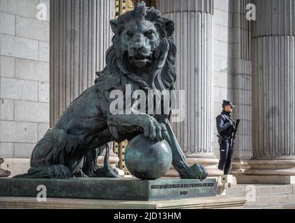 Eine bewaffnete Wache, die neben einer Löwenstatue vor dem Palacio de las Cortes, Madrid, Spanien, steht Stockfoto