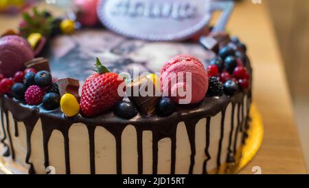 Ein Kuchen zum Kindergeburtstag mit Beeren, Früchten, Makronen, die ein süßes persisches Kätzchen darstellen Stockfoto