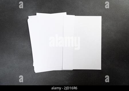 Weiße Visitenkarte Blatt papier A4 Stapel auf einem dunklen Tisch. Hochformat reinigen A4. Stockfoto