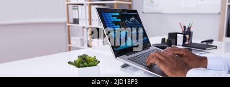 Nahaufnahme der Geschäftsmann Analyse von Graphen auf Laptop am Arbeitsplatz im Büro Stockfoto