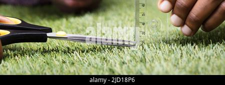 Nahaufnahme eines Mannes Schneiden grüne Gras Gemessen mit Lineal Stockfoto