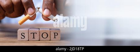 Nahaufnahme einer Hand, die Zigarette über Holz- Anschlagblöcke Stockfoto