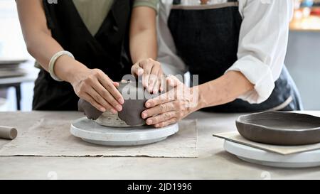 Beschnittenes Bild, Hände, die eine Tontöpfer machen, eine Tontöpfer in der Werkstatt Formen. Handgefertigtes, handgefertigtes Kochgeschirr. Stockfoto