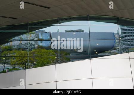 Spiegelungen des BMW Museums und der Umgebung in der Glasfassade der BMW World München, 19.4.22 Stockfoto