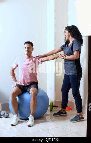 Professionelle Physiotherapeutin, die mit weiblichen Patienten im Rehabilitationszentrum arbeitet Stockfoto