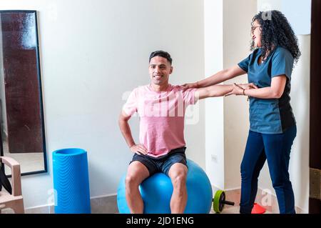 Professionelle Physiotherapeutin, die mit weiblichen Patienten im Rehabilitationszentrum arbeitet Stockfoto