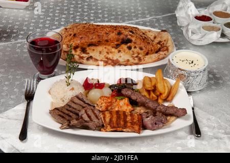 Auf dem Esstisch stehen Shish Kebab, Pita-Brot und Fruchtsaft. Grill aus Huhn und Lamm. Stockfoto