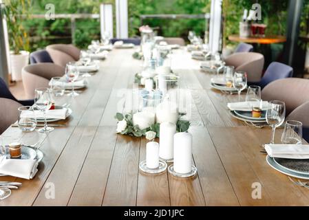 Wunderschöne Hochzeitsdekoration im Freien in der Stadt. Kerzen, getrocknete Blumen und Accessoires, Blumensträuße und Gläser auf dem Tisch mit Leinentischdecke auf frisch verheiratet Stockfoto