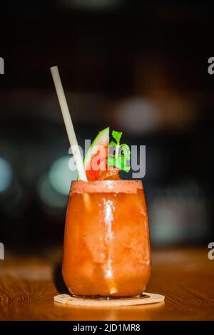 Gesundes Getränk. Nahaufnahme von Wassermelonen-Shakes mit Fruchtscheibe und Minze, Bio-Papierstroh in transparentem Glas auf dem Tisch in der Bar. Kalt, tropisch Stockfoto