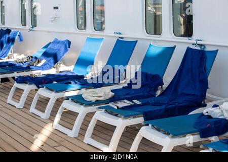 Plastikliegen mit blauen Handtüchern auf einem Schiff Stockfoto