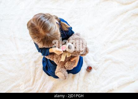 Kind behandelt einen Bären. Das Spiel des Arztes. Selektiver Fokus. Stockfoto