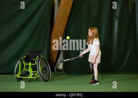 Mädchen mit künstlichem Bein beim Tennisspielen Stockfoto