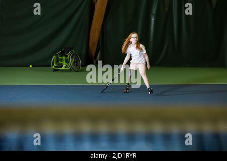 Mädchen mit künstlichem Bein beim Tennisspielen Stockfoto