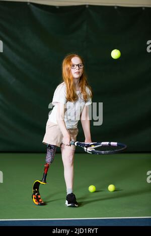 Mädchen mit künstlichem Bein beim Tennisspielen Stockfoto